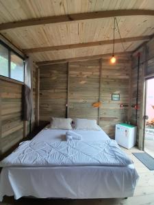 a large bed in a room with wooden walls at Santa Monica Hospedaria in Praia do Rosa