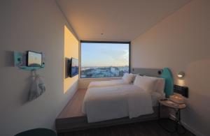 een slaapkamer met een wit bed en een groot raam bij SOJO HOTEL CAN THO in Can Tho