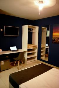 1 dormitorio con cama, escritorio y espejo en Conde Hotel Piura, en Piura