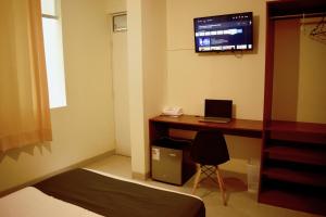 um quarto com uma secretária com um computador portátil e uma televisão em Conde Hotel Piura em Piura