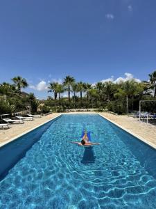 a person laying on a surfboard in a swimming pool at Masseria Boscorotondo in Scicli