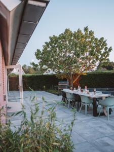 um pátio com uma mesa, cadeiras e uma árvore em Luxurious Family Villa with swimmingpool big garden and jacuzzi em Zeewolde