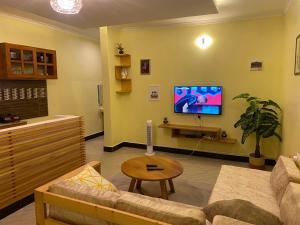 a living room with a couch and a tv at Town Retreat Moshi in Moshi