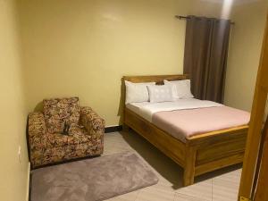 a small bedroom with a bed and a chair at Town Retreat Moshi in Moshi