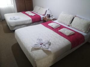 two beds in a hotel room with white flowers on them at Hotel Casa La Riviera in Bogotá