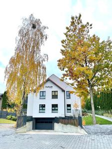 ein weißes Gebäude mit einem Baum davor in der Unterkunft Apartament FOREST - HOME APART in Ostróda