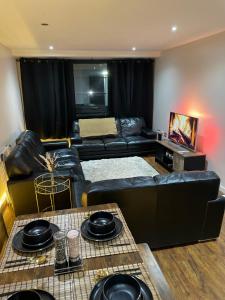 un salon avec un canapé en cuir noir et une table dans l'établissement Luxury 1 or 2 bedroom Apartment Birmingham City Centre, à Birmingham