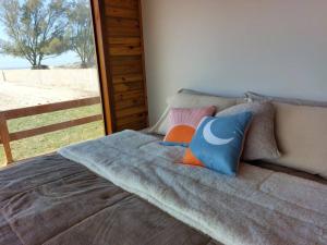 uma cama com almofadas num quarto em Cabana das Dunas beira mar em Jaguaruna