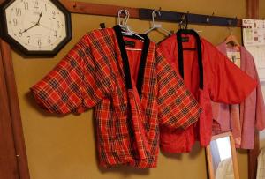 a group of shirts hanging on a wall with a clock at とんかつ&ヒーリングハウスえん in Shimmachi