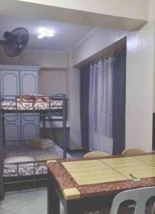 Zimmer mit einem Tisch und Etagenbetten sowie einem Tisch und Stühlen in der Unterkunft Baguio Breeze Condo2 in Baguio City