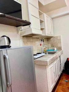a kitchen with white cabinets and a stainless steel refrigerator at Ina Mansion 65 in Baguio