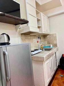 a kitchen with white cabinets and a stainless steel refrigerator at Baguio Breeze Condo2 in Baguio