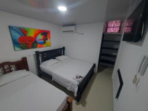Un pequeño dormitorio con 2 camas y una escalera. en HOTEL CASA BLANCA, en Aguachica