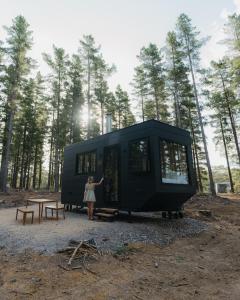 a woman standing in front of a black tiny house at CABN Kuitpo Forest in Kuitpo