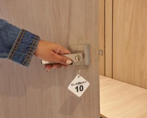 une personne déverrouillant une porte avec une étiquette sur celle-ci dans l'établissement Elemont Hotel, à Medellín