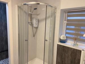 a shower with a glass door in a bathroom at The old blue shop in Milford Haven