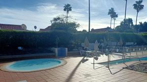 a swimming pool with chairs and umbrellas in a resort at Bungalow en el sur de Gran Canaria in Las Palmas de Gran Canaria +14 photos
