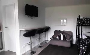 a living room with two stools and a tv on the wall at Methven Retreat Tiny House in Methven