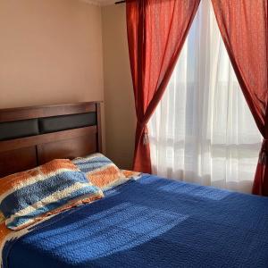 Un dormitorio con una cama azul y una ventana en Tomé, Playa Bellavista, Departamento balcón con vista al mar, en Tomé