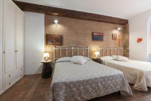 a bedroom with two beds and a brick wall at Antico Podere Il Bugnolo in Poggibonsi