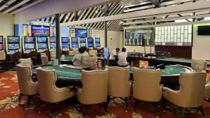 uma sala de poker com mesas e cadeiras e pessoas a jogar poker em Coconut Palms Resort & Diamond Casino em Port Vila