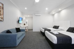 Habitación de hotel con 2 camas y sofá en Shellharbour Village Motel, en Shellharbour