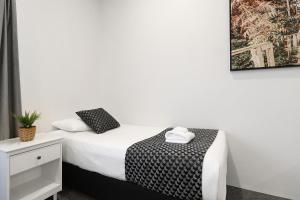 1 dormitorio con 1 cama con manta blanca y negra en Shellharbour Village Motel, en Shellharbour