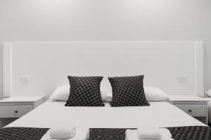 a white bed with black and white pillows on it at Shellharbour Village Motel in Shellharbour