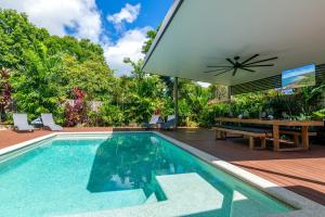 an outdoor swimming pool with a table and an umbrella at Paradiso in Port Douglas