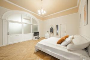 a white bedroom with a bed and a tv at Best Seasons La Famiglia in Budapest