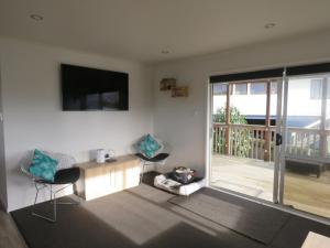 a living room with a table and chairs and a television at Hihi Getaway in Mangonui