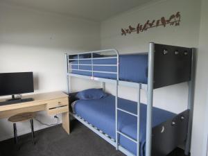 a bedroom with two bunk beds and a desk at Hihi Getaway in Mangonui