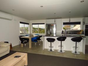 a kitchen and living room with a bar and chairs at Hihi Getaway in Mangonui