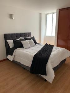 ein großes Bett mit schwarzweißer Bettwäsche und Kissen in der Unterkunft HERMOSO APARTAMENTO SANTA BARBARA in Bogotá