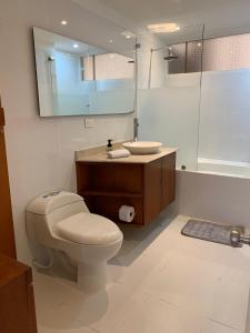 ein Badezimmer mit einem WC, einem Waschbecken und einem Spiegel in der Unterkunft HERMOSO APARTAMENTO SANTA BARBARA in Bogotá