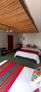 a bedroom with two beds and a wooden ceiling at Uros Waliski Lodge in Puno