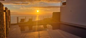 a sunset over the ocean from a balcony of a building at Casa Mar Azul in Arco da Calheta