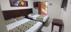 Habitación de hotel con 2 camas y mesa en hotel paseo colon inn, en Barranquilla