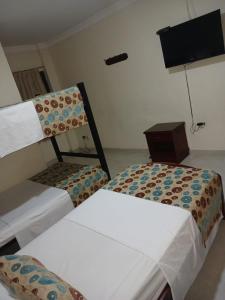 um quarto com duas camas e uma tv nele em hotel paseo colon inn em Barranquilla