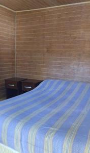 a bedroom with a bed with a blue comforter at Suite doble Coñaripe in Coñaripe