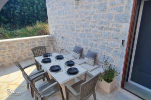 a table and chairs on a patio with a stone wall at Mani Tu With Breathtaking View 2 in Éxo Nímfion