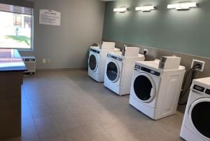 a laundry room with three washing machines and a counter at Baymont by Wyndham McAllen Pharr in McAllen