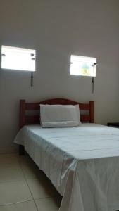 a bed in a bedroom with two windows at Flat Japaratinga Beach in Japaratinga