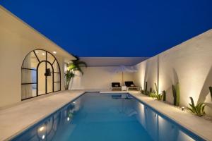 a swimming pool in a building with a blue ceiling at The Grand Daha Luxury Villas in Seminyak