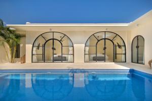 a house with a swimming pool with three windows at The Grand Daha Luxury Villas in Seminyak