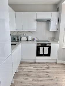 una cucina bianca con armadi bianchi e forno nero di Private Luxury One Bedroom Apartment with parking a Palmers Green