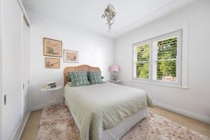 a white bedroom with a bed and a window at CHES4 - Woollahra Getaway in Sydney