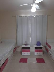 a bedroom with two drawers and a bed and a fan at Sobrado confortável a uma quadra do mar. in Matinhos