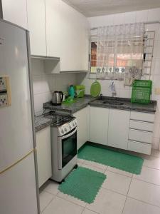 a kitchen with white cabinets and a green rug at Sobrado confortável a uma quadra do mar. in Matinhos