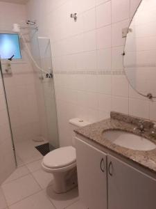 a bathroom with a toilet and a sink and a shower at Sobrado confortável a uma quadra do mar. in Matinhos +17 photos
